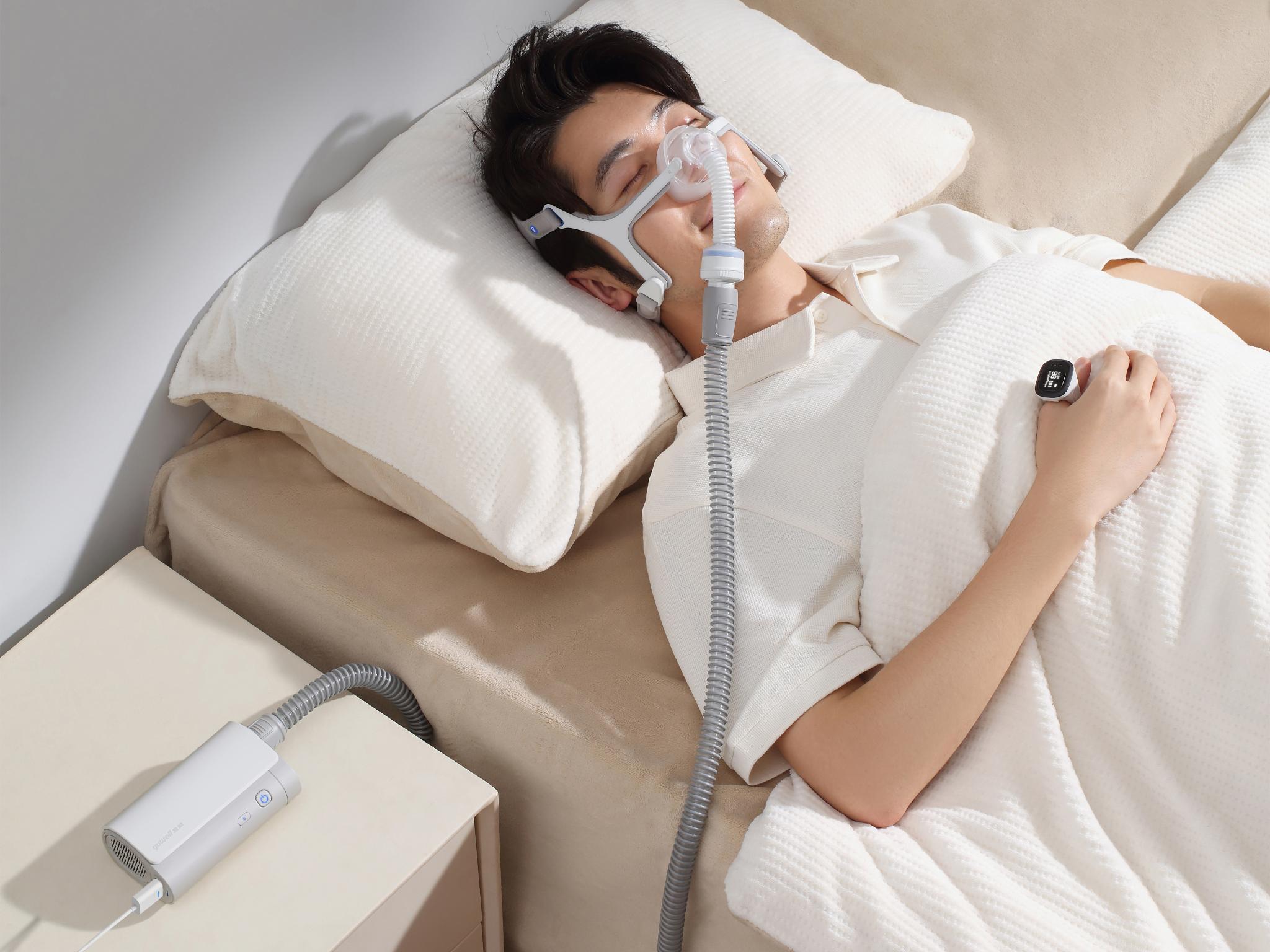 Użytkownik śpiący z aparatem CPAP Yuwell Pocket i pierścieniem SpO2